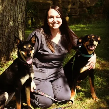 Amber kneeling on the grass next to two dogs